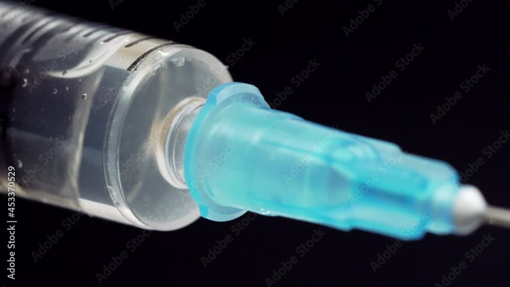 Macro Shot of Syringe with Vaccine Solution On Black Background. Medication Slowly Injected Using Syringe Macro Shot of Syringe with Vaccine Solution On Black Background. Medication Slowly Injected Using Syringe
