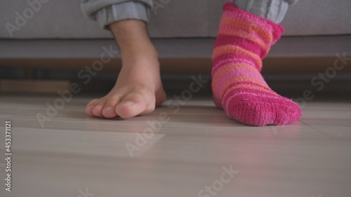 Bare Feet of Caucasian Male Waking Up in The Morning and Putting On Funny Warm Colorful Socks