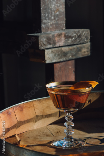 Manhattan whiskey bourbon cocktail in vintage gold coupe glass on barrel in sunlight 