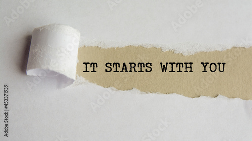 IT STARTS WITH YOU. words. text on grey paper on torn paper background