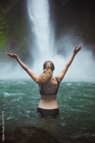 Young woman with waterfall in background in Costa Rica 