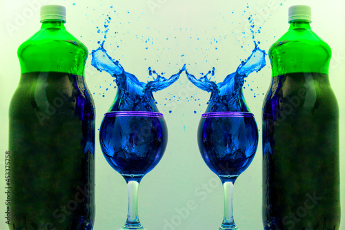 Garrafas de vidro verde contendo suco de uva e duas taças com liquido azul em splash. photo