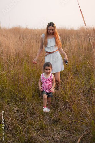 Madre e hija caminando por un campo al atardecer 