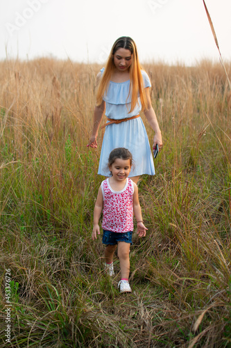 Madre e hija caminando por un campo al atardecer 