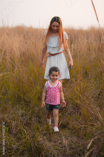 Madre e hija caminando por un campo al atardecer 