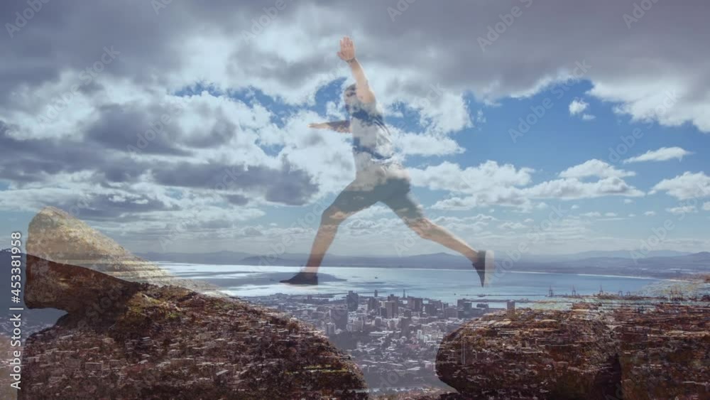 Composite of senior man running and jumping on rocks by coast, and cloudy blue sky over sea Composite of senior man running and jumping on rocks by coast, and cloudy blue sky over sea