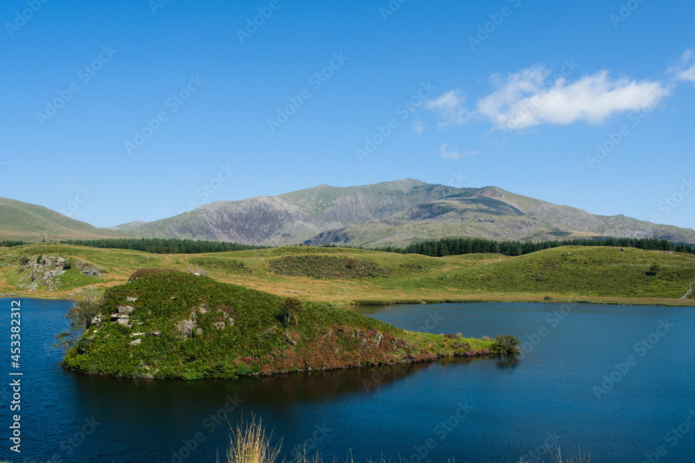 Dramatic Welsh mountain landscape. Snowdonia national park. Small secluded island at pretty lake Dywarchen. Landscape view with copy space.