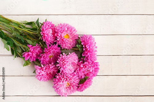 A beautiful bouquet of pink asters lies on a white wooden background  copy space