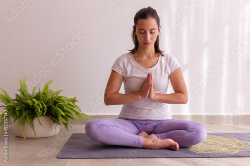 Young beautiful woman meditating at home