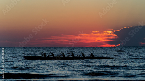 Valokuva Rowing crew in silhouette on water against pastel sunset sky