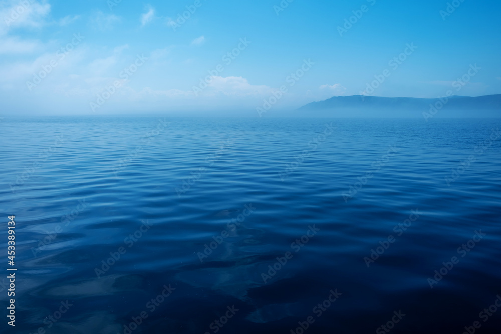 Waves on surface of water with cloudy sky and mountain. Copy space Waves on surface of water with cloudy sky and mountain. Copy space