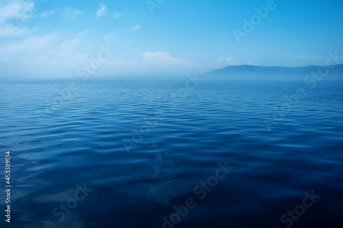 Waves on surface of water with cloudy sky and mountain. Copy space