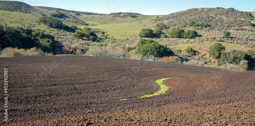 S shaped irrigation ditch in plowed field in Central California near Guadalupe California USA photo