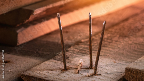 Close-up of old rusty nails sticking out of dark old boards on the floor
