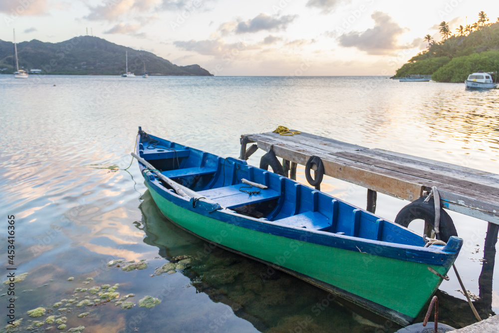 A green wooden boat docked in a handcrafted deck of Providencia Island in Colombia