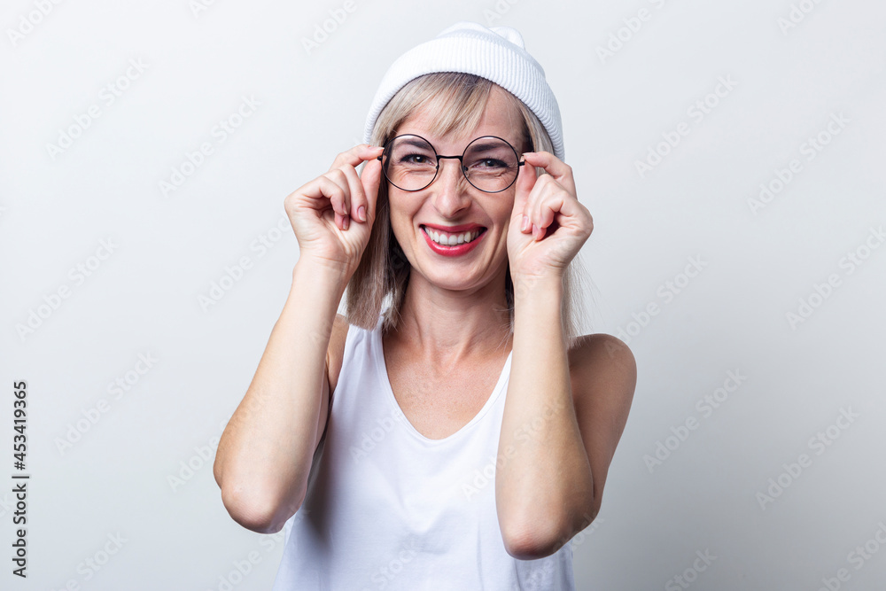 Cheerful young woman in a hat holding glasses on a light background Cheerful young woman in a hat holding glasses on a light background