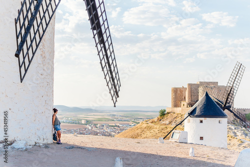 Woman leaning against the facade of a windmill while contemplating the landscape