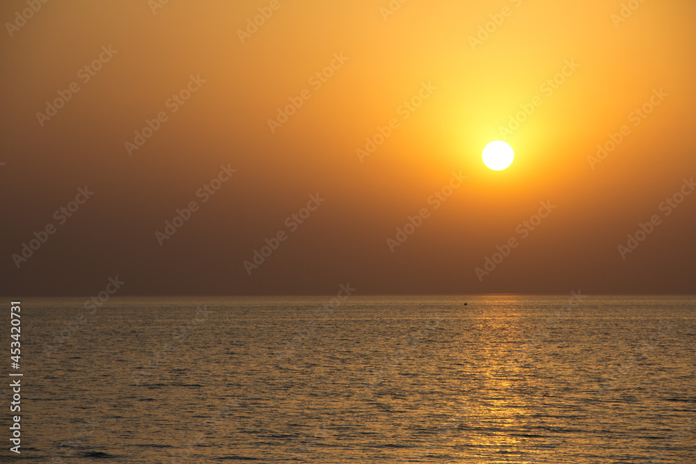Orange sun setting over the ocean. No boats, no people, space for copy.