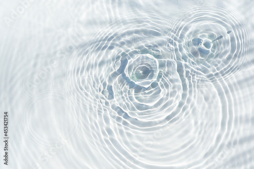 Water drops fall on the transparent surface of the water and the shadow of a palm leaf. Top view, flat lay