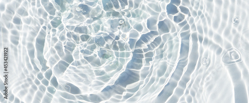 Water droplets fall on the transparent surface of the water in sunlight. Top view, flat lay. Banner