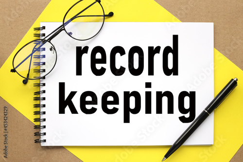 Record Keeping, text on notepad on bright stiff backing and craft background photo