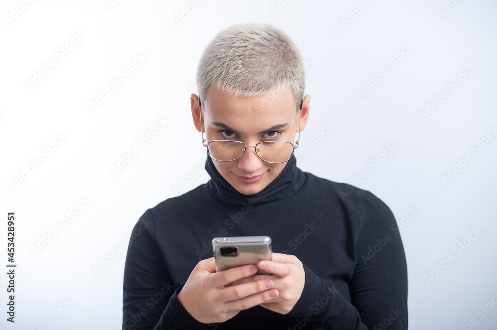 Young caucasian woman with short hair uses a smartphone on a white background. Young caucasian woman with short hair uses a smartphone on a white background.