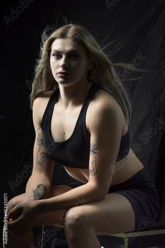 Young beautiful blonde girl is engaged in the gym. Photographed in a low key.