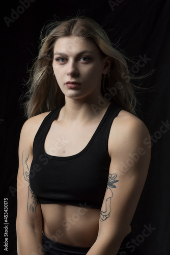 Young beautiful blonde girl is engaged in the gym. Photographed in a low key.