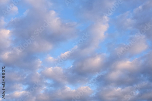 White fluffy clouds running across a sunny blue sky. Wonderful summer air background