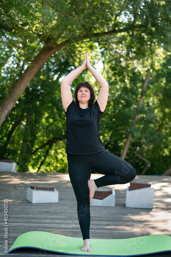 Young beautiful girl teaches yoga in the park. Girl teaches a new tree pose. Outdoor yoga photo