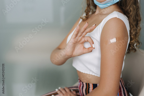 Middle seceltion of woman getting vaccinated immunity giving ok sign hand. Concept of recommended inoculation. Female with face mask on shin after covid-19 vaccine