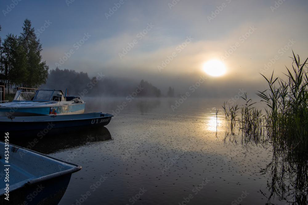 Boats at the pier. Early morning. Fog on the river. Beautiful sunrise in the summer by the river.