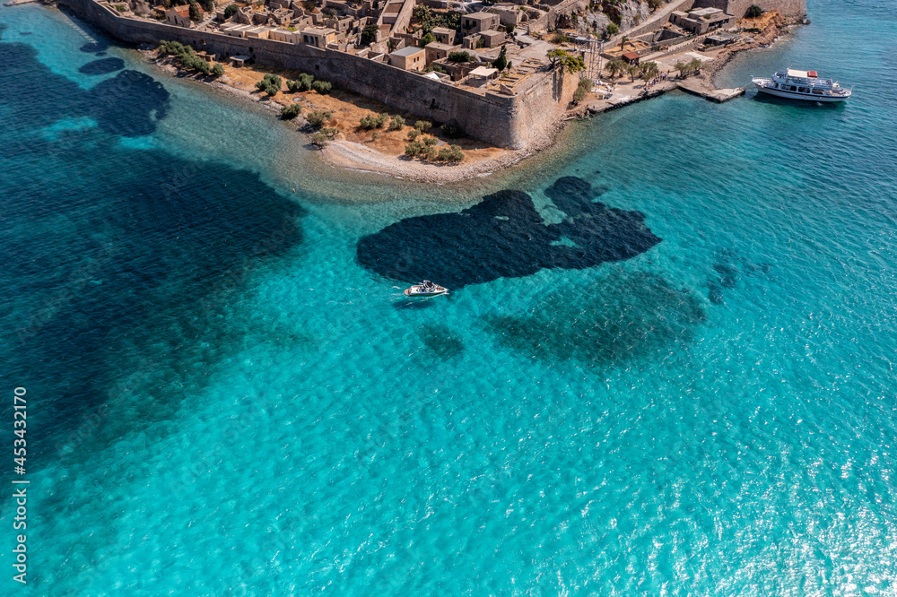 panoramic view of Spinalonga island with ships and turquoise sea filmed from a drone 