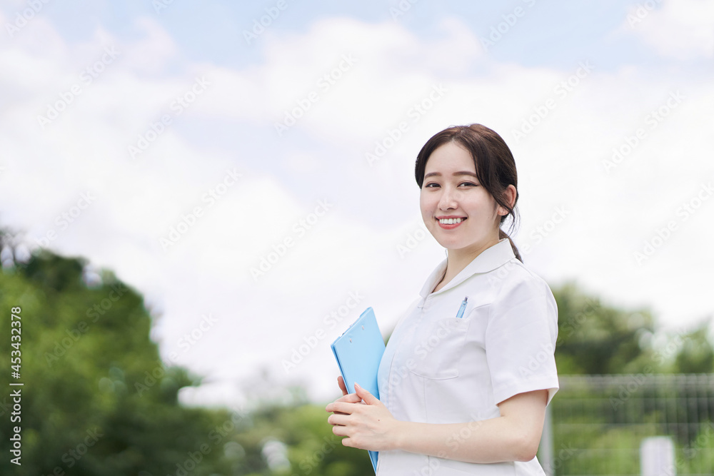 青空背景で笑顔で立つ女性看護師 青空背景で笑顔で立つ女性看護師