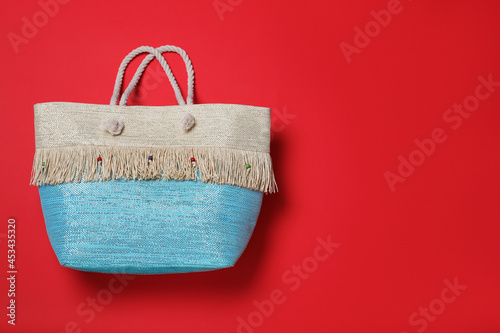 Stylish beach bag on red background, top view. Space for text