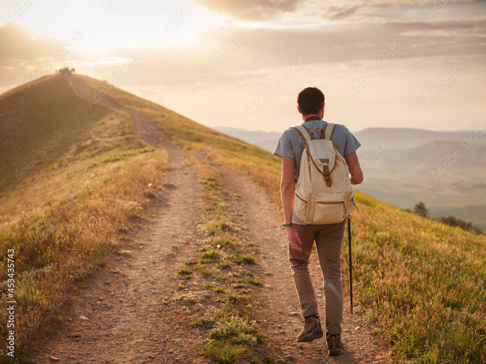 Young man travels alone on the backdrop of the mountains