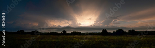 sun rays in the sky between clouds over the field after rain, panorama