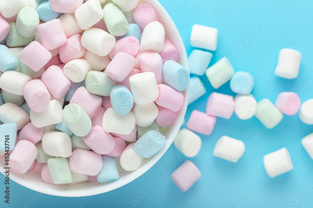 Colorful marshmallows in a bowl on soft blue background Colorful marshmallows in a bowl on soft blue background