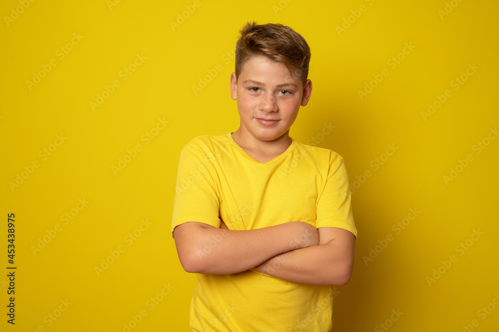 Cheerful boy folded his arms isolated over yellow background. Cheerful boy folded his arms isolated over yellow background.