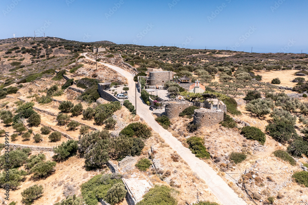 a panoramic view of the ancient centuries-old mills against the backdrop of mountains and olive groves of Crete filmed from a drone 