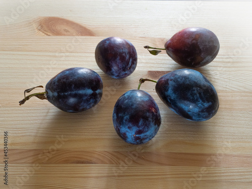 Ripe plums lie on a wooden table