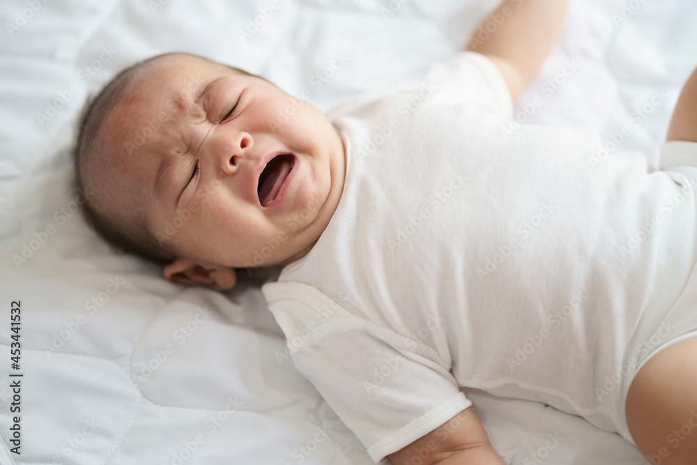 Asian newborn crying baby boy. New born child tired and hungry in bed.Children cry. Bedding for kids. Infant screaming. Healthy little kid shortly after birth. Asian newborn crying baby boy. New born child tired and hungry in bed.Children cry. Bedding for kids. Infant screaming. Healthy little kid shortly after birth.