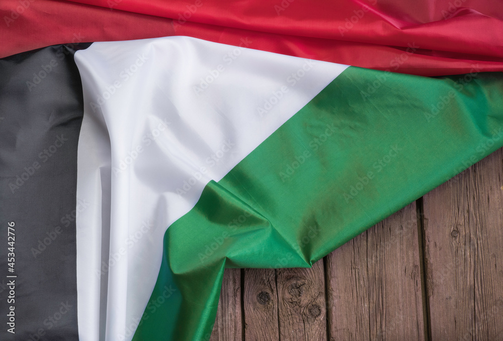 The flag of the United Arab Emirates lies on a brown wooden background with space for text or image.