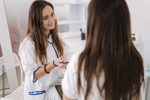 Female doctor using sphygmomanometer with stethoscope checking blood pressure to a patient in the hospital. Young woman modern in clinic. Back view