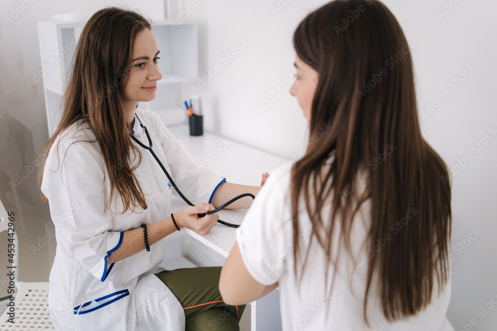 Female doctor using sphygmomanometer with stethoscope checking blood pressure to a patient in the hospital. Young woman modern in clinic Female doctor using sphygmomanometer with stethoscope checking blood pressure to a patient in the hospital. Young woman modern in clinic