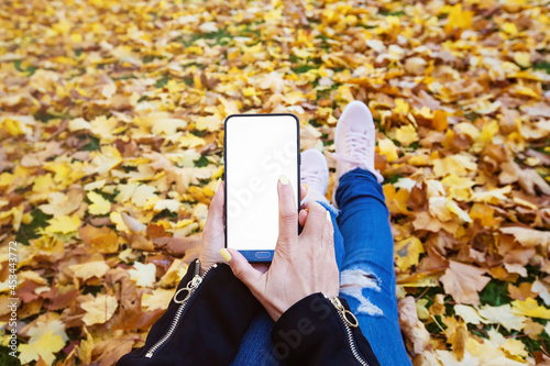 Young Hipster Woman hand using application with menu on smartphone While Autumn fall background