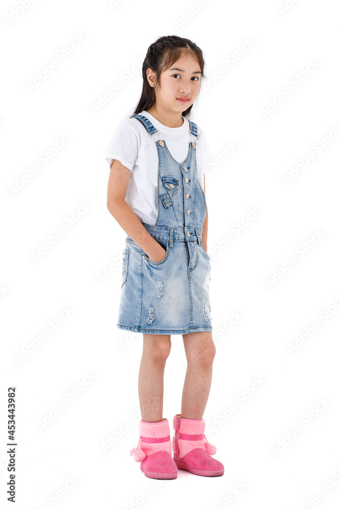 Portrait isolated studio shot of young long hair pretty cute girl in t shirt and denim skirt overalls with pink boots stand look at camera posing put hands in pocket in front of white background Portrait isolated studio shot of young long hair pretty cute girl in t shirt and denim skirt overalls with pink boots stand look at camera posing put hands in pocket in front of white background