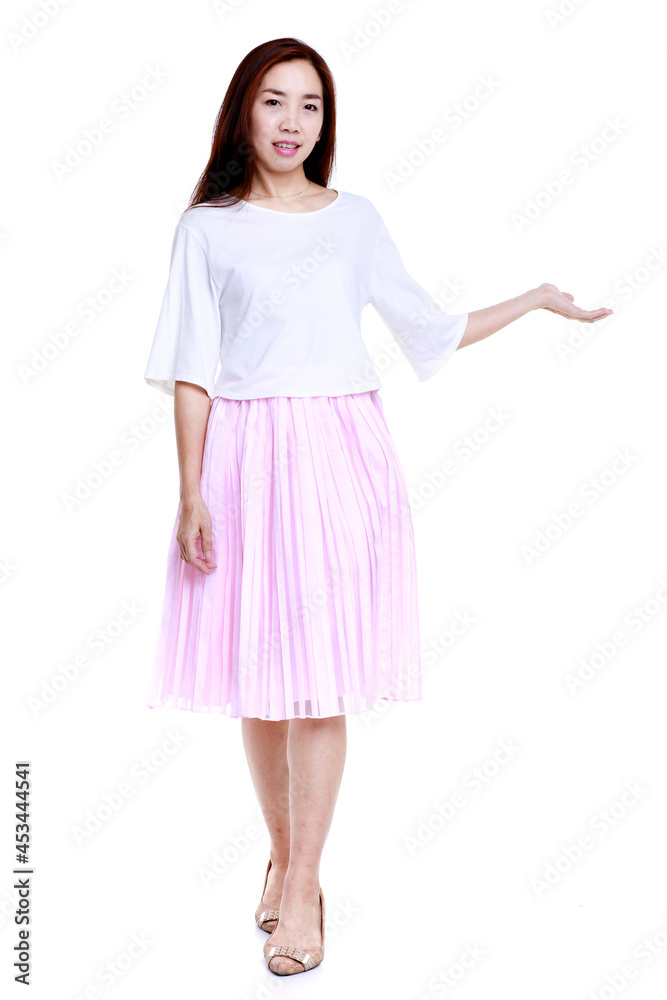Full body of smiling young Asian female in white blouse and pink skirt pointing with hand aside isolated on white background Full body of smiling young Asian female in white blouse and pink skirt pointing with hand aside isolated on white background
