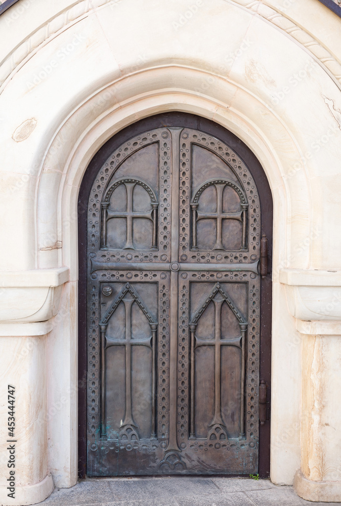Arched metal doors of the church with carvings. Forged gates of the monastery.