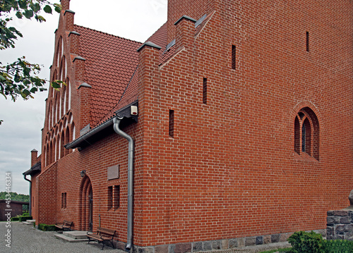 General view and architectural details of the Evangelical Augsburg Church in the village of Wejsuny in Masuria, Poland, built in 1910 in red brick in the neo-Gothic style. photo